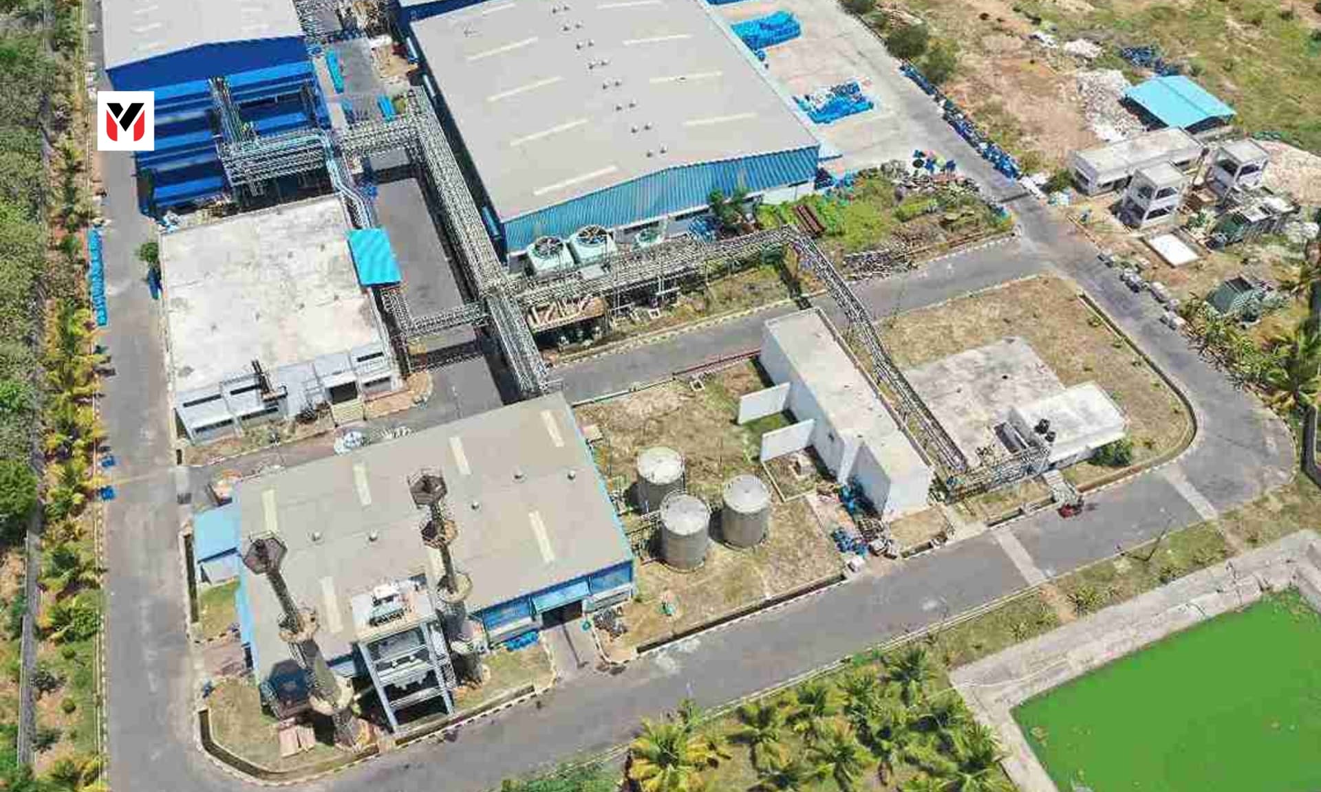 Aerial view of a mixed industrial zone near Chennai with factory rooftops, logistics roads, and green landscaping