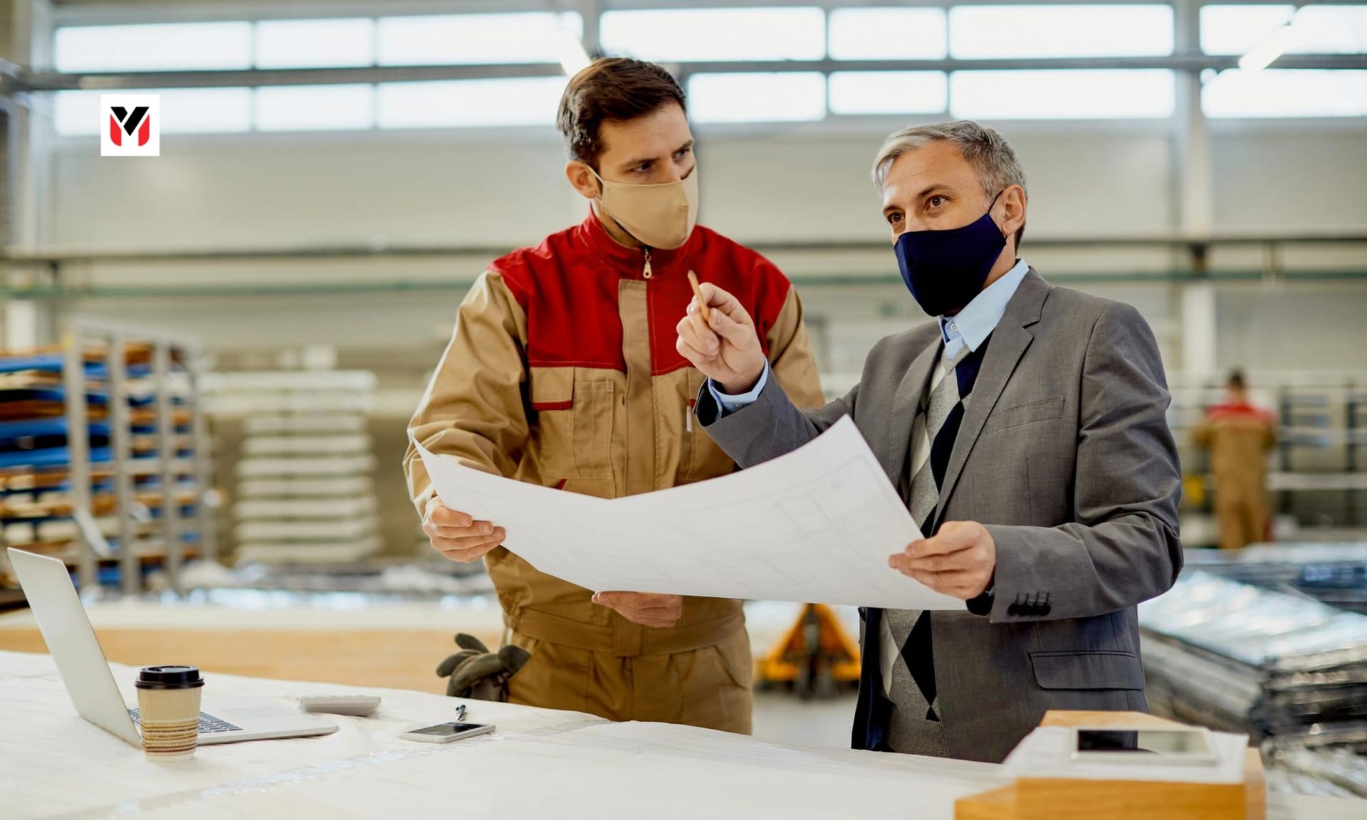 A supervisor guiding a young operator on a lathe in a small factory.